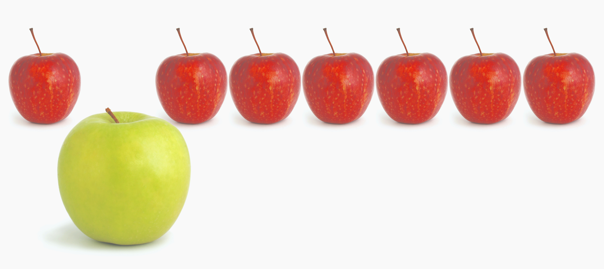 Standing out from the crowd...green apple stands out from a row of red apples.  Business concepts include leadership, individuality, creativity, lateral thinking.